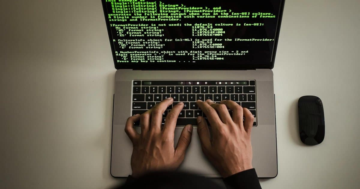 Hands typing code on a laptop with programming text on screen, indoors, featured image for Qué eligen realmente los agentes de código con IA, explicado para CEOs